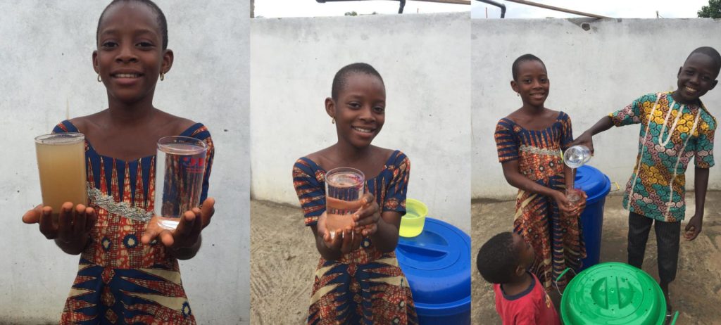 Smiling girl holding two cups of water, one filled with clean water and the other with dirty water, showcasing the importance of water quality. A boy assists her by pouring clean water into another cup, highlighting community efforts in promoting access to safe drinking water.