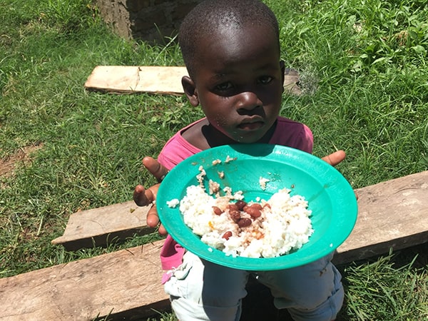 Young girl holding up a plate of rice and beans