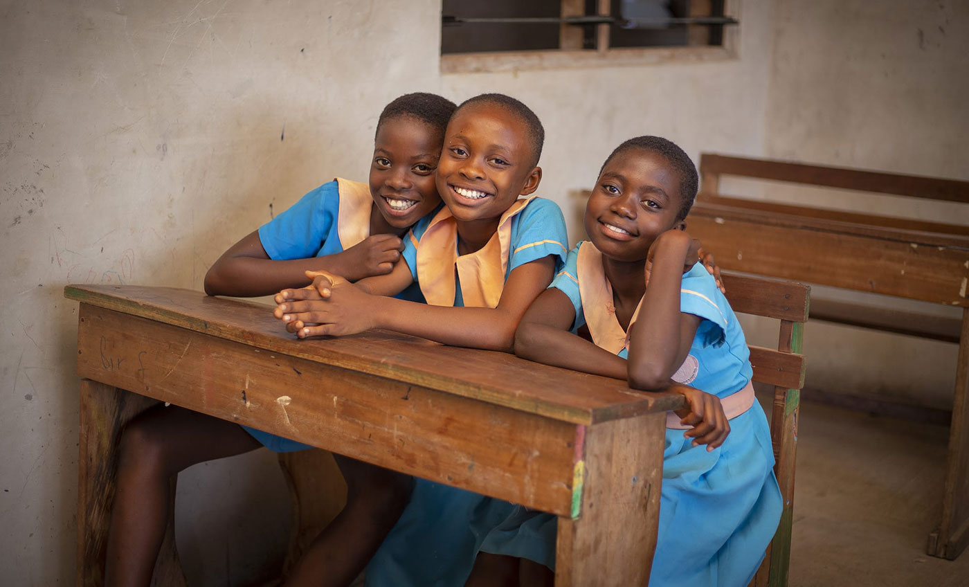 3 Girls in light blue uniforms at a rustic school