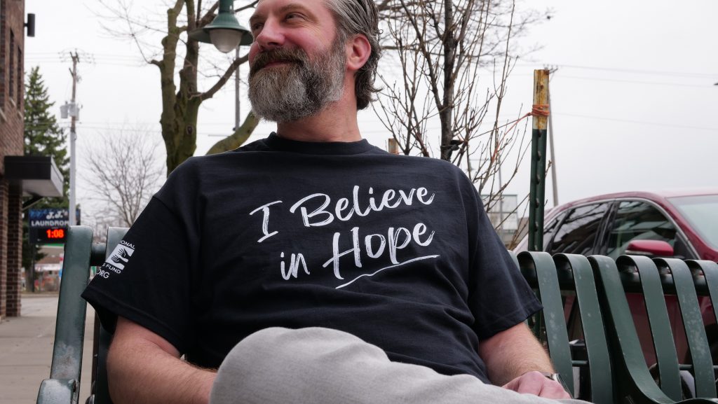 Man sitting on a bench wearing his ICF Hope shirt